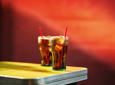 Global Coca-Cola Real Magic Cheers 2 Bell Glasses with Straws on Table.png